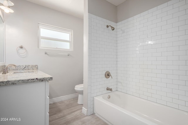 full bathroom featuring wood-type flooring, toilet, vanity, and tiled shower / bath