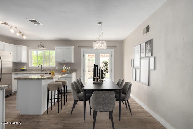 dining area with dark wood-type flooring, a wealth of natural light, sink, and an inviting chandelier