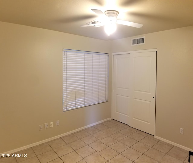 unfurnished bedroom with light tile patterned floors, ceiling fan, and a closet