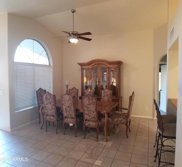 tiled dining space featuring ceiling fan and high vaulted ceiling