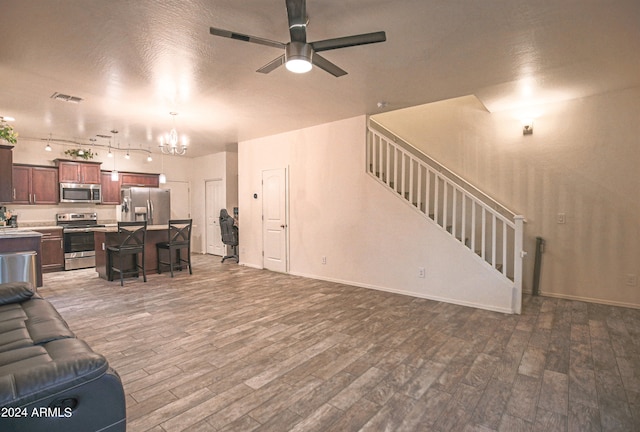 living room featuring ceiling fan with notable chandelier and dark hardwood / wood-style flooring