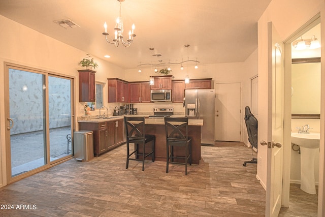 kitchen featuring a kitchen island, a breakfast bar, stainless steel appliances, sink, and decorative light fixtures