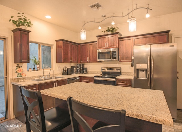 kitchen with hanging light fixtures, sink, a center island, appliances with stainless steel finishes, and light stone counters