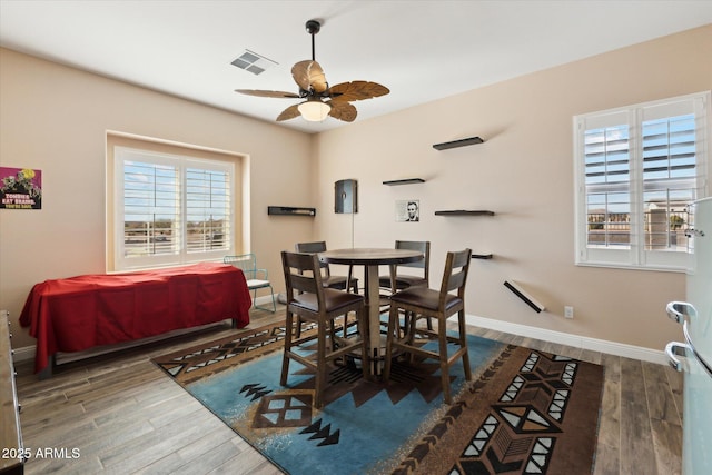 dining room with ceiling fan, a wealth of natural light, and dark hardwood / wood-style floors