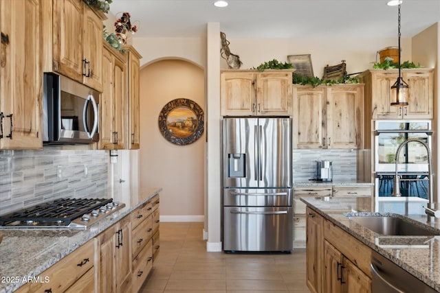 kitchen with appliances with stainless steel finishes, tasteful backsplash, decorative light fixtures, and light stone countertops