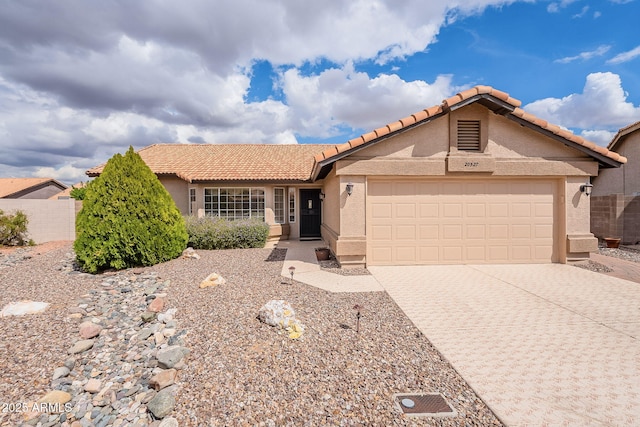 view of front of home featuring stucco siding, an attached garage, decorative driveway, and fence