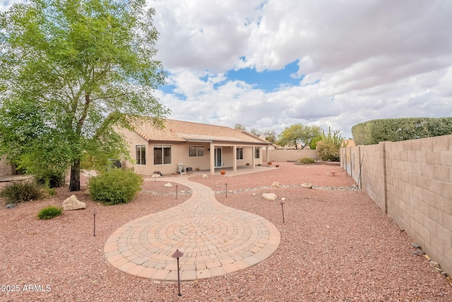 back of house featuring a tiled roof, a patio area, fence, and stucco siding