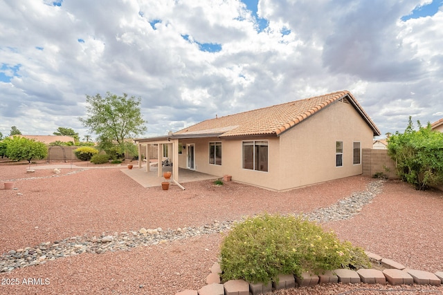 rear view of property featuring a patio area, stucco siding, a tiled roof, and a fenced backyard