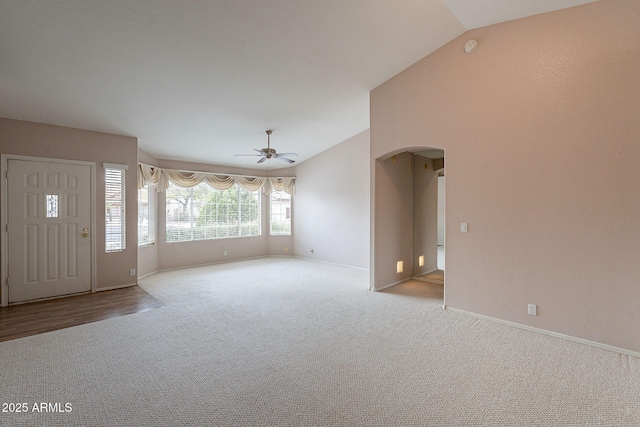 interior space with arched walkways, carpet floors, baseboards, ceiling fan, and vaulted ceiling