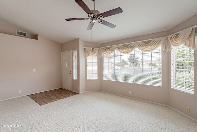 carpeted spare room with visible vents, baseboards, a ceiling fan, and vaulted ceiling