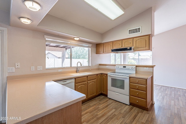 kitchen with visible vents, a sink, under cabinet range hood, white appliances, and a peninsula