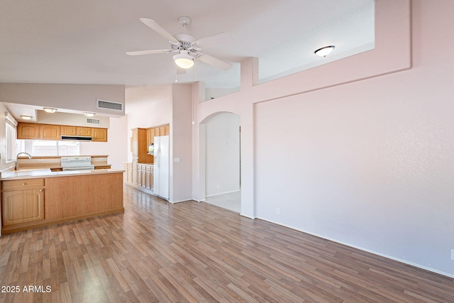 kitchen with visible vents, a sink, under cabinet range hood, white appliances, and a peninsula