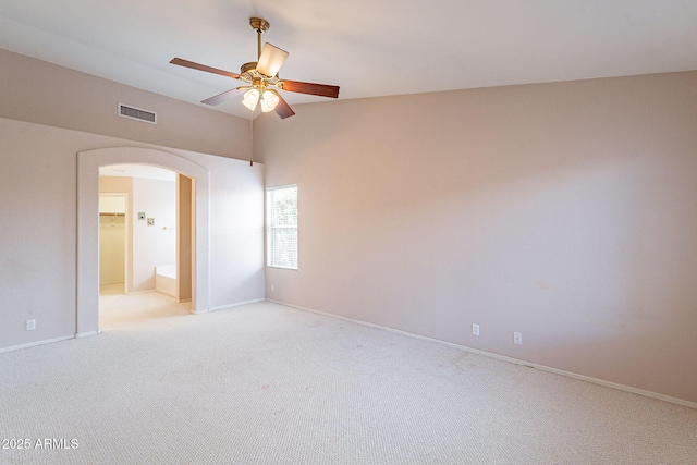 unfurnished room with visible vents, light carpet, a ceiling fan, arched walkways, and baseboards