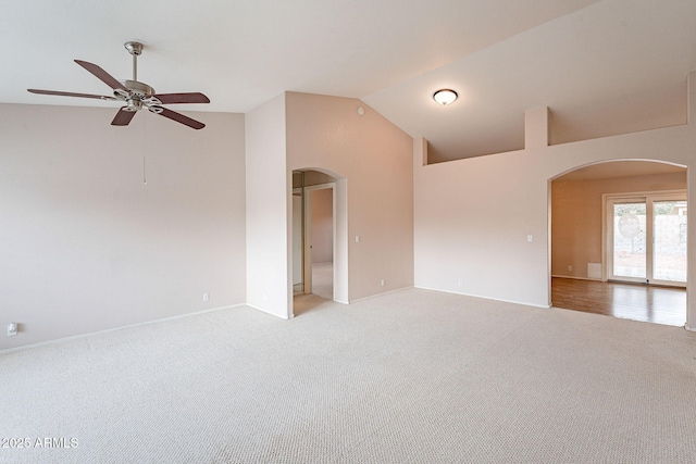 spare room with baseboards, light colored carpet, arched walkways, high vaulted ceiling, and a ceiling fan