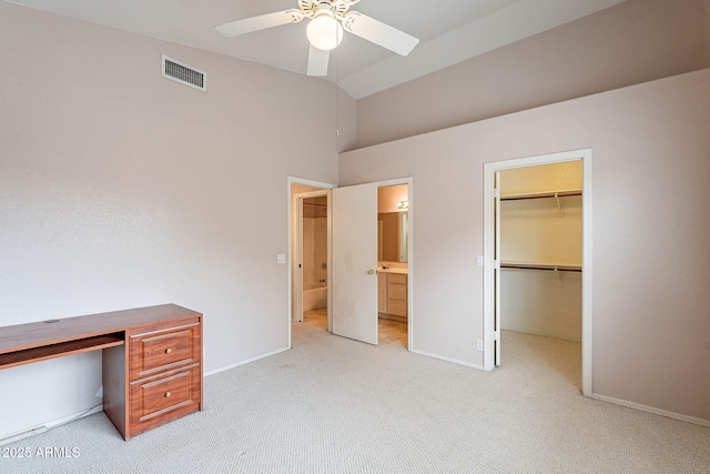 unfurnished bedroom with visible vents, light carpet, ensuite bath, a spacious closet, and vaulted ceiling