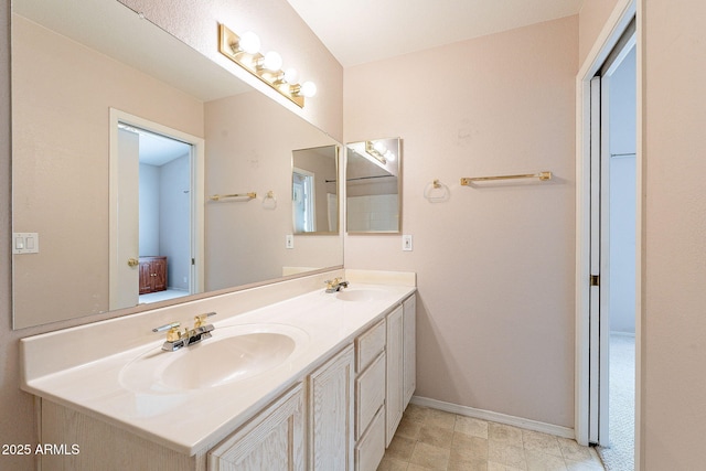 full bathroom featuring a sink, baseboards, and double vanity