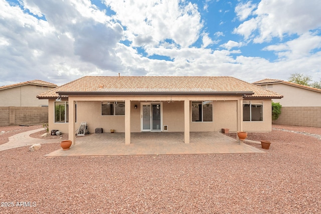 rear view of property featuring stucco siding, a patio, a fenced backyard, and a tile roof