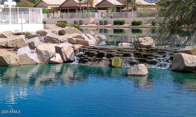 view of swimming pool with a water view and fence