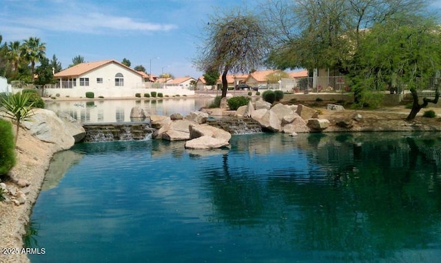 view of swimming pool with a water view and fence