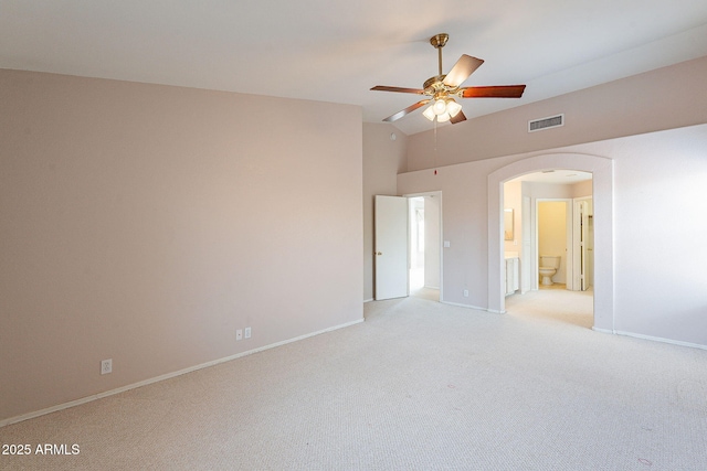 unfurnished bedroom with visible vents, baseboards, lofted ceiling, light carpet, and arched walkways