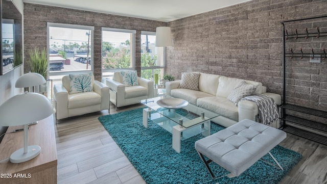 living area with brick wall and wood finished floors