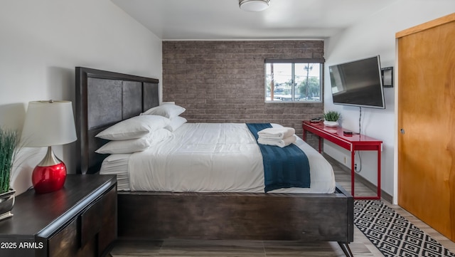 bedroom with brick wall and wood finished floors