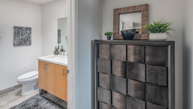 bathroom with toilet, wood finished floors, and vanity