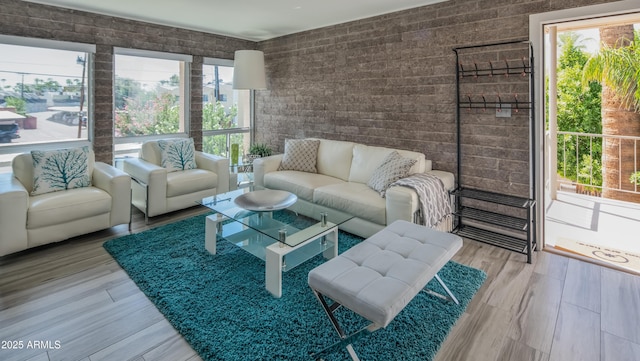 living area with brick wall and wood finished floors