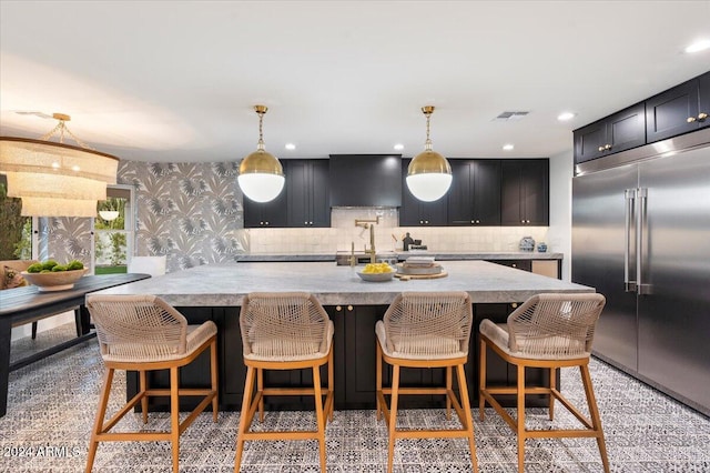 kitchen with tasteful backsplash, built in fridge, decorative light fixtures, a breakfast bar, and premium range hood