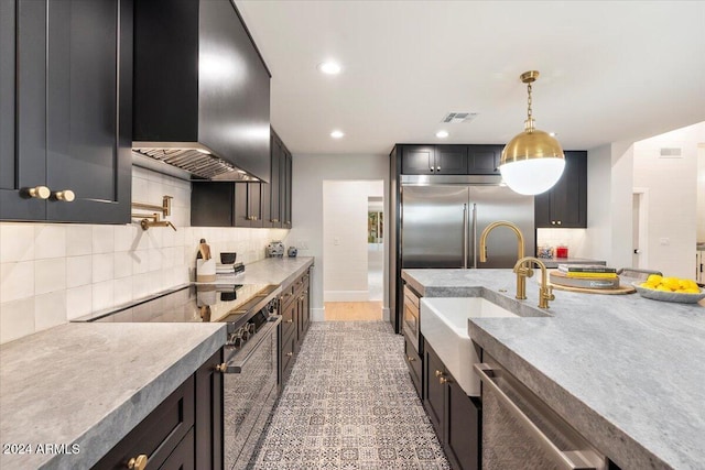 8014 E Del Tesoro Dr, Scottsdale, AZ 85258 - kitchen with premium appliances, wall chimney range hood, tasteful backsplash, a sink, and pendant lighting