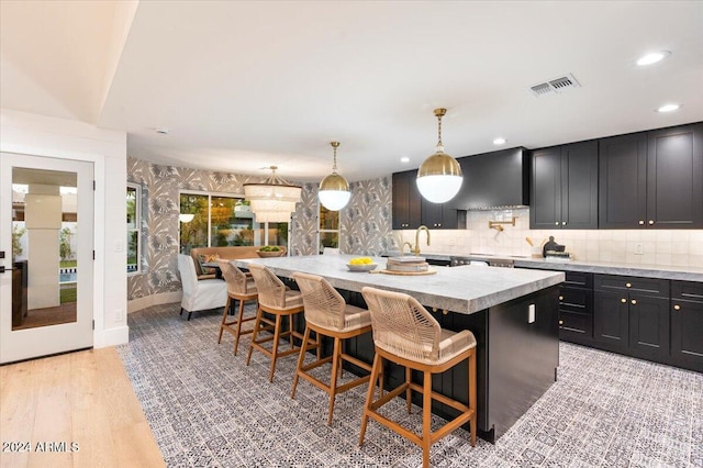 kitchen with a breakfast bar area, custom range hood, a center island, pendant lighting, and light wood-type flooring