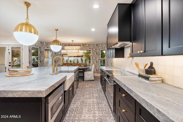 8014 E Del Tesoro Dr, Scottsdale, AZ 85258 - kitchen featuring a sink, light countertops, wall chimney range hood, decorative light fixtures, and appliances with stainless steel finishes