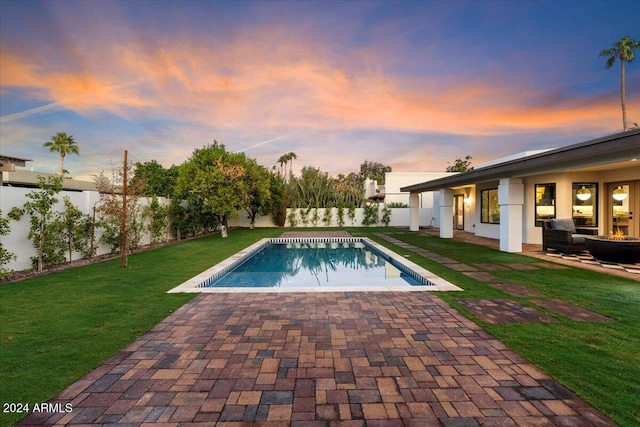 pool at dusk with a yard and a patio area