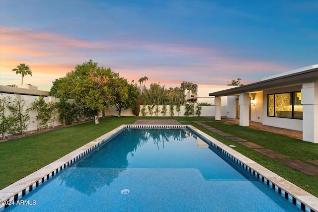 pool at dusk featuring a lawn