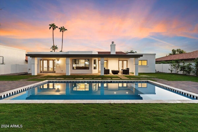 pool at dusk with a yard and a patio