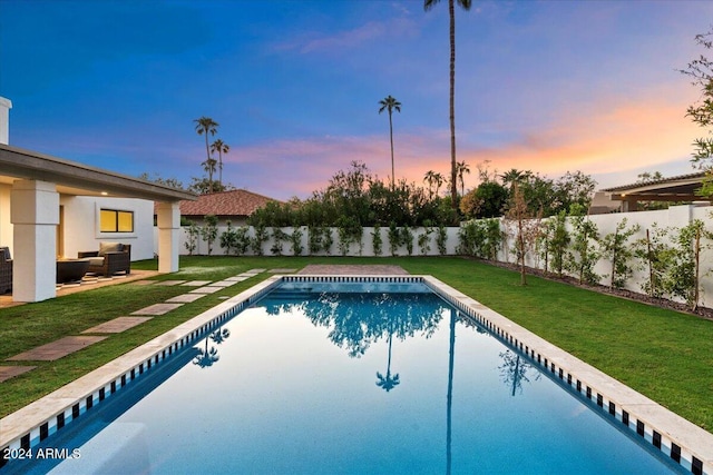 pool at dusk with a patio, a lawn, and outdoor lounge area