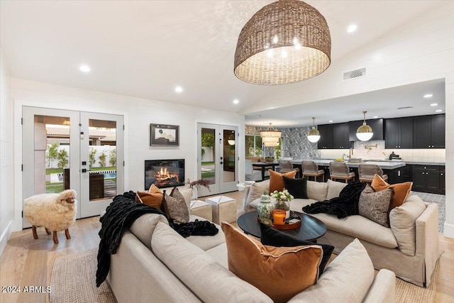 living room with lofted ceiling, french doors, and light hardwood / wood-style floors