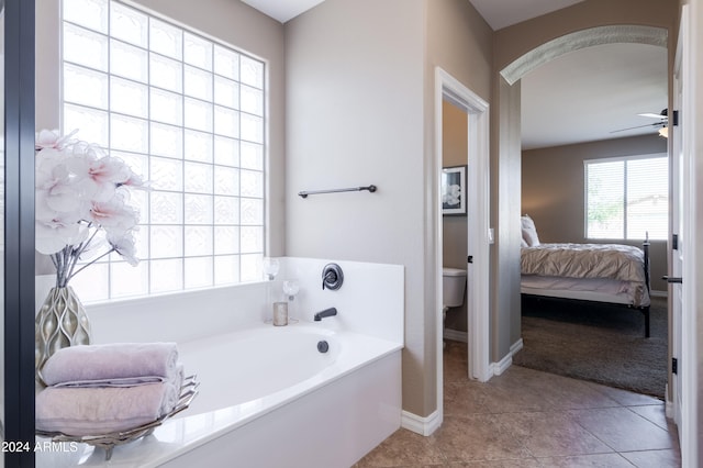 bathroom featuring tile patterned floors, toilet, a tub to relax in, and ceiling fan