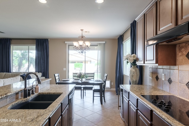 kitchen featuring black electric cooktop, sink, light stone counters, and a wealth of natural light