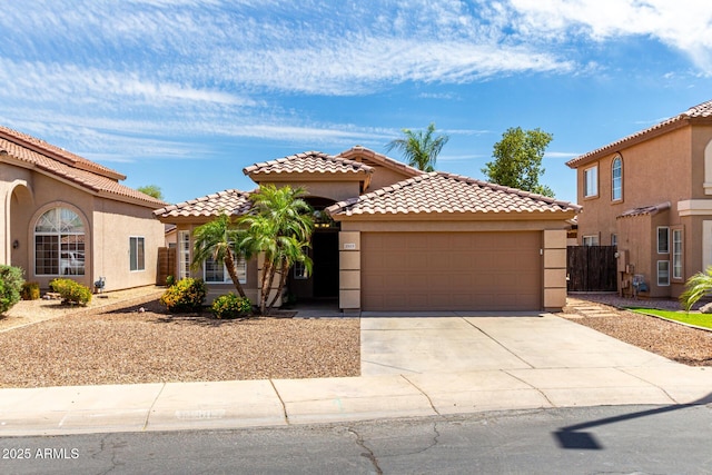 mediterranean / spanish-style house featuring concrete driveway, a tiled roof, an attached garage, and stucco siding