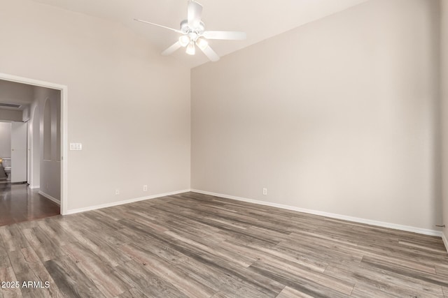 unfurnished room with baseboards, ceiling fan, wood finished floors, and vaulted ceiling