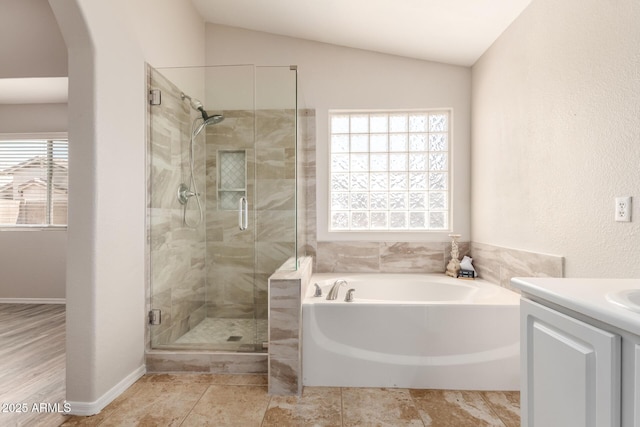 bathroom featuring vanity, baseboards, vaulted ceiling, a bath, and a stall shower