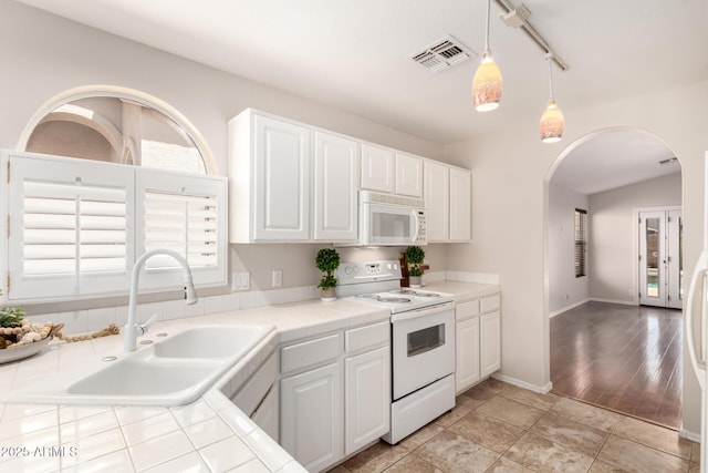 kitchen featuring visible vents, a sink, white appliances, tile countertops, and arched walkways