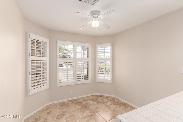 empty room featuring ceiling fan, visible vents, and baseboards