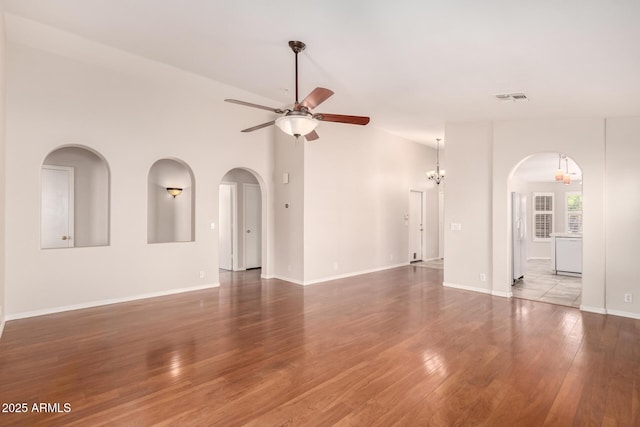 unfurnished living room featuring arched walkways, ceiling fan, wood finished floors, and visible vents