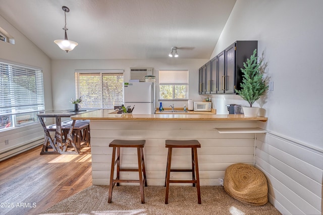 2273 Trail Cir, Overgaard, AZ 85933 - kitchen featuring white appliances, lofted ceiling, a peninsula, plenty of natural light, and a kitchen bar