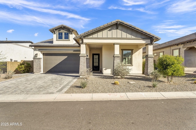 craftsman inspired home featuring a tiled roof, decorative driveway, and stucco siding