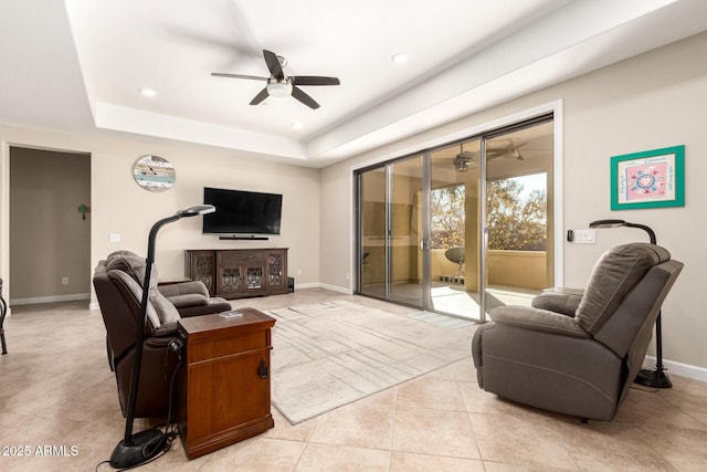 living room featuring light tile patterned floors, a raised ceiling, and ceiling fan