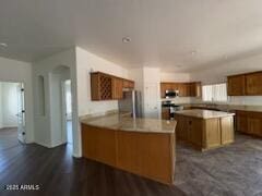 500 S Santa Fe Trl, Cornville, AZ 86325 - kitchen with brown cabinetry, a peninsula, freestanding refrigerator, arched walkways, and light countertops