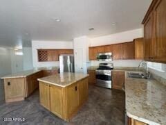 500 S Santa Fe Trl, Cornville, AZ 86325 - kitchen with appliances with stainless steel finishes, a kitchen island, a sink, and brown cabinetry